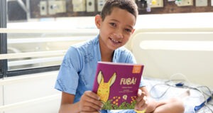 Criança segurando livro infantil do projeto Leitura para Todos da Aliansce Sonae
